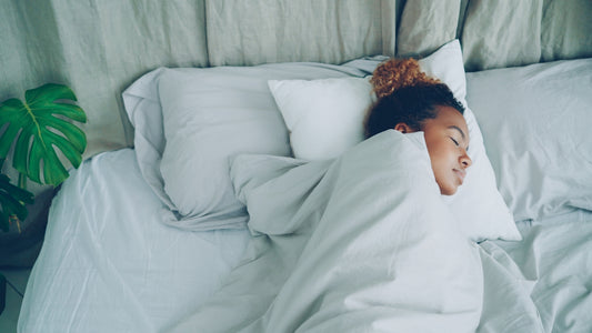 A young woman sleeping peacefully in a white bed.